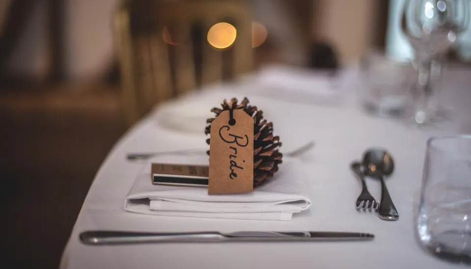 Place card tied to a pinecone on a white place setting